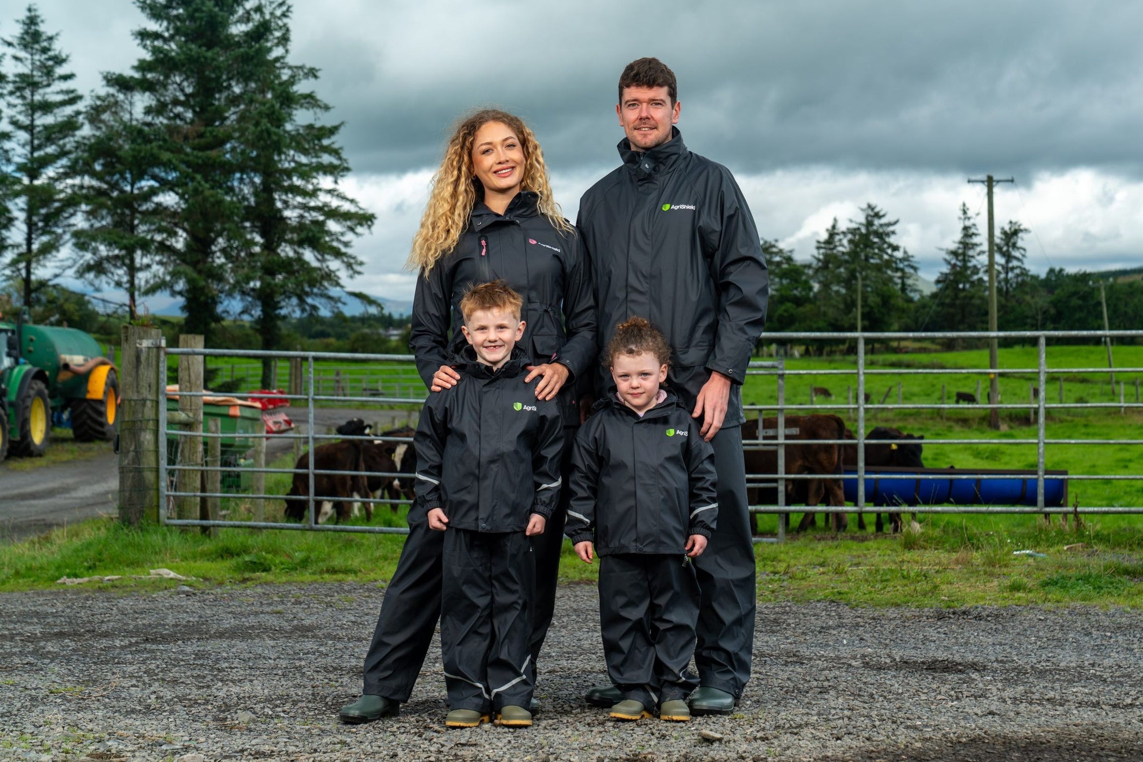 A farming family in waterproofs at the yard gate