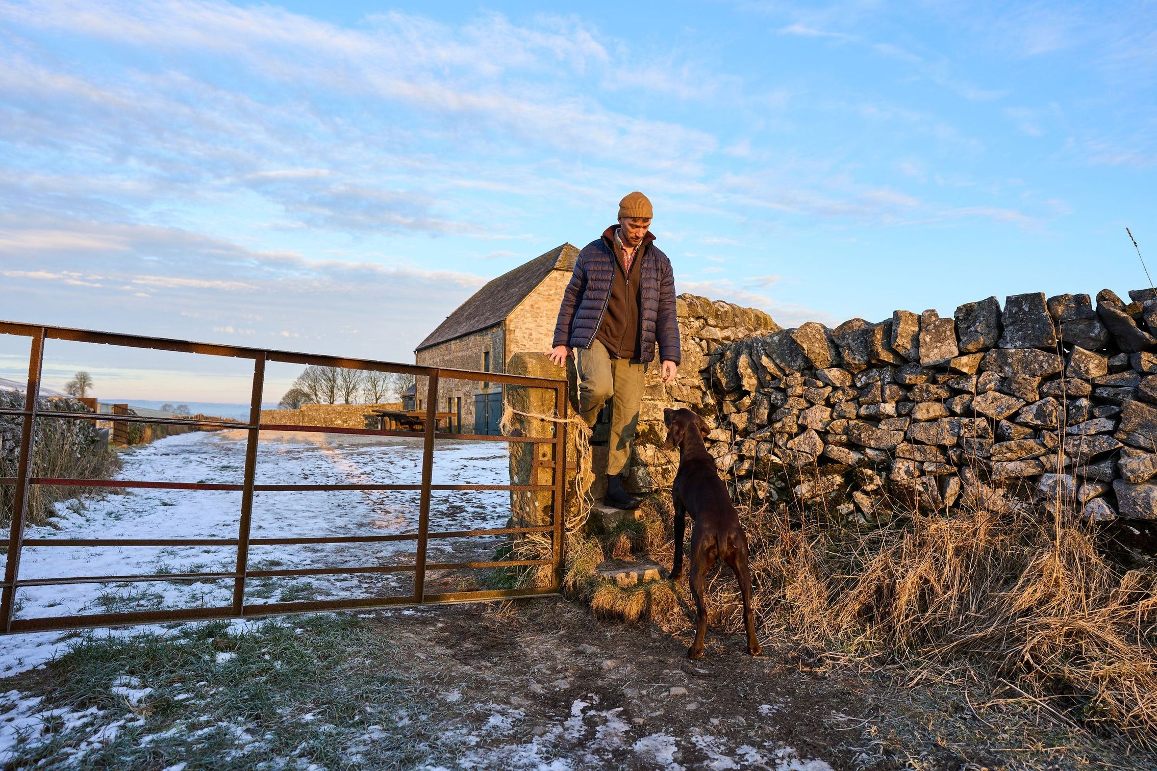 Farmer and dog at a gate in the snow
